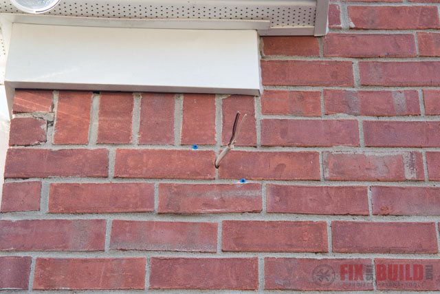 wire extending through hole in red brick wall