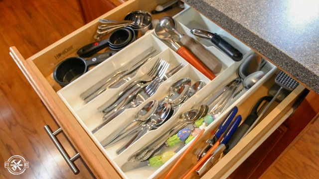 white plastic drawer organizer in messy wooden drawer