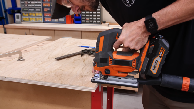 a man is cutting out a small square in a sheet of plywood to make a toekick.