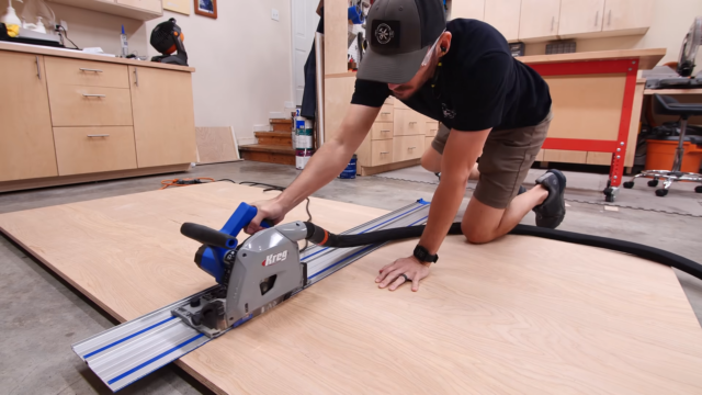 man cutting plywood with track saw on the ground